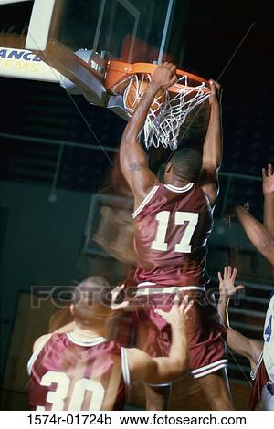 Stock Image - Rear view of a basketball player slam dunking. Fotosearch