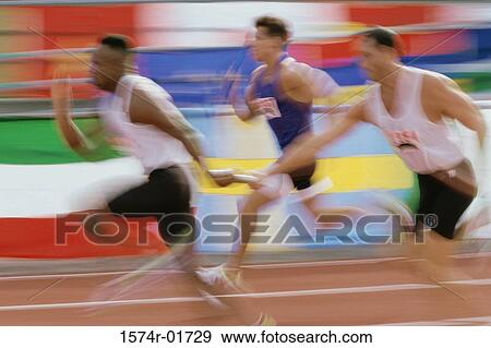 Stock Photo - Side profile of runners exchanging baton at a relay race. Fotosearch