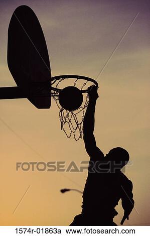 Silhouette of a man slam dunking a basketball View Large Photo Image Stock Image - Silhouette of a man slam dunking a basketball. Fotosearch