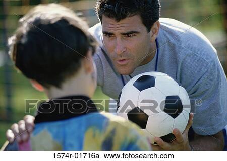 Stock Image - Soccer coach standing with his hand on a boy's shoulder. Fotosearch
