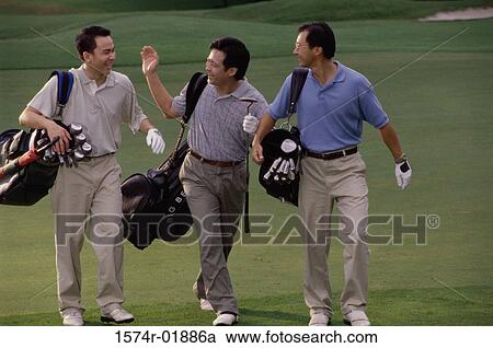 Stock Image - Three men carrying golf bags at a golf course. Fotosearch