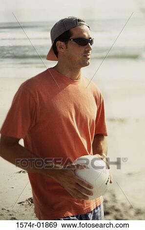 Young man holding a volleyball on the beach View Large Photo Image Stock Photo - Young man holding a volleyball on the beach. Fotosearch