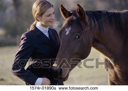 Young woman standing with a horse View Large Photo Image Stock Image - Young woman standing with a horse. Fotosearch
