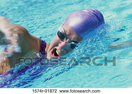 Stock Image - Young woman swimming in a swimming pool. Fotosearch