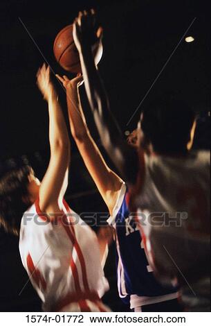 Stock Image - Young women reaching for a basketball. Fotosearch