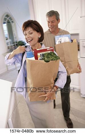 Stock Image - Couple carrying grocery bags. Fotosearch