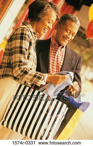 Couple examining a garment while shopping View Large Photo Image Stock Image - Couple examining a garment while shopping. Fotosearch