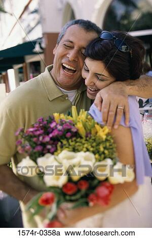 Couple smiling holding a bouquet of flowers View Large Photo Image Stock Image - Couple smiling holding a bouquet of flowers. Fotosearch