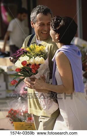 Stock Image - Couple smiling holding a bouquet of flowers. Fotosearch
