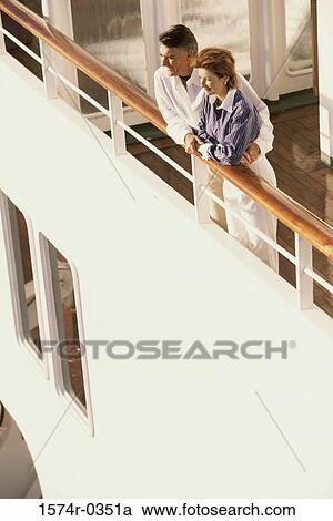 Stock Image - Couple standing against the railing of a ship. Fotosearch
