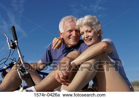Stock Image - Low angle view of a senior couple holding a bicycle. Fotosearch