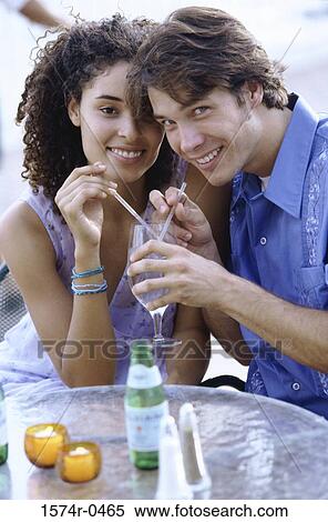 Stock Photography - Portrait of a young couple sitting together smiling. Fotosearch