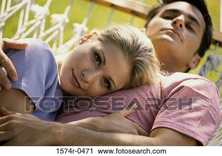 Stock Image - Portrait of a young woman lying with her head on a young man's stomach. Fotosearch