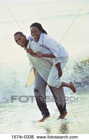 Stock Photograph - Portrait of a young woman riding piggyback on a young man. Fotosearch