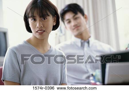 Portrait of a young woman with a young man behind her View Large Photo Image Stock Photograph - Portrait of a young woman with a young man behind her. Fotosearch