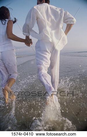 Rear view of a young couple at the beach View Large Photo Image Stock Image - Rear view of a young couple at the beach. Fotosearch