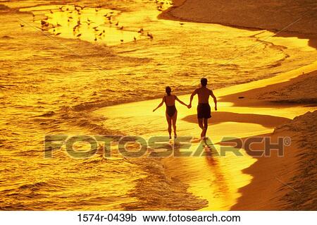 Rear view of a young couple walking on the beach holding hands View Large Photo Image Stock Image - Rear view of a young couple walking on the beach holding hands. Fotosearch