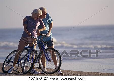 Senior couple holding bicycles at the beach View Large Photo Image Stock Photo - Senior couple holding bicycles at the beach. Fotosearch