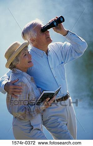 Senior couple looking through a pair of binoculars View Large Photo Image Stock Image - Senior couple looking through a pair of binoculars. Fotosearch