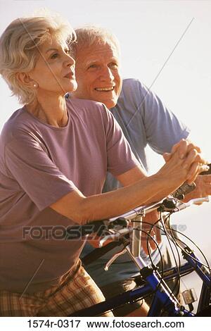 Senior couple standing with bicycles View Large Photo Image Stock Photo - Senior couple standing with bicycles. Fotosearch