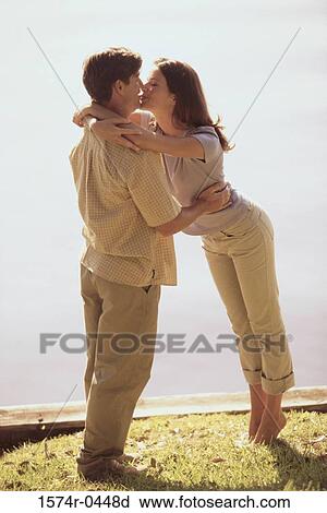 Stock Image - Side profile of a young couple kissing. Fotosearch