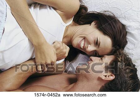 Young couple lying down on a bed smiling View Large Photo Image Stock Image - Young couple lying down on a bed smiling. Fotosearch