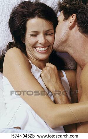 Young couple lying down on a bed smiling View Large Photo Image Stock Image - Young couple lying down on a bed smiling. Fotosearch