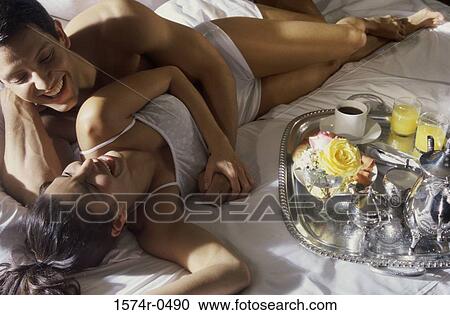 Young couple lying down on a bed smiling View Large Photo Image Stock Image - Young couple lying down on a bed smiling. Fotosearch