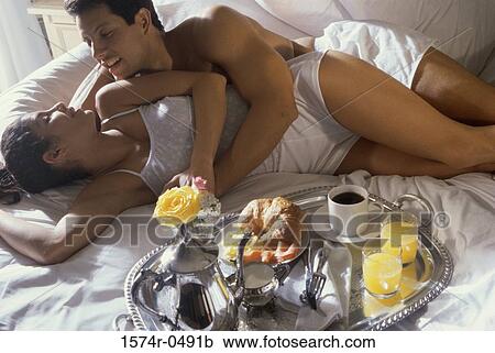 Young couple lying down on a bed smiling View Large Photo Image Stock Image - Young couple lying down on a bed smiling. Fotosearch