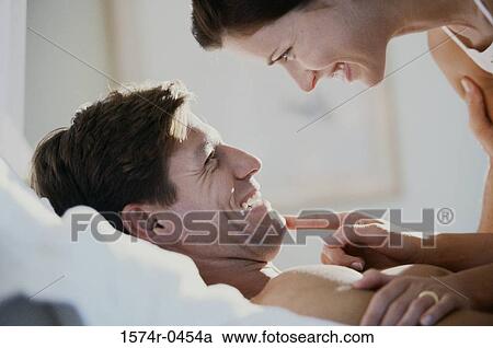 Young couple lying down on a bed smiling. View Large Photo Image Stock Image - Young couple lying down on a bed smiling.. Fotosearch