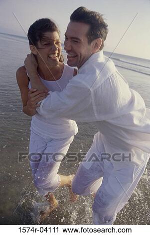 Stock Image - Young couple playing at the beach. Fotosearch