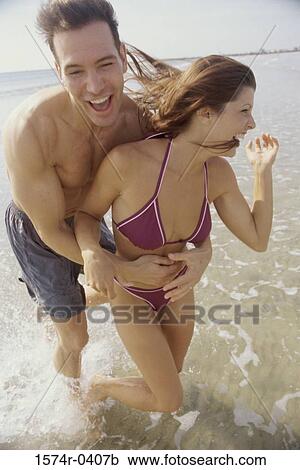 Stock Image - Young couple playing on the beach. Fotosearch