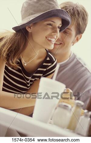 Young couple sitting at a table View Large Photo Image Picture - Young couple sitting at a table. Fotosearch