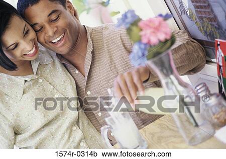 Young couple sitting together at a table View Large Photo Image Stock Image - Young couple sitting together at a table. Fotosearch
