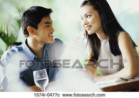 Young couple sitting together at a table View Large Photo Image Stock Image - Young couple sitting together at a table. Fotosearch
