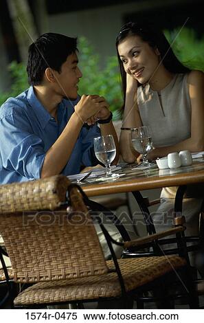 Young couple sitting together at a table View Large Photo Image Stock Photography - Young couple sitting together at a table. Fotosearch