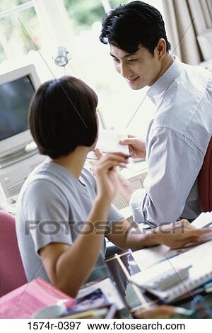 Stock Photo - Young couple sitting together at an office. Fotosearch