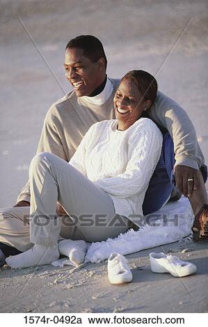 Young couple sitting together at the beach View Large Photo Image Stock Image - Young couple sitting together at the beach. Fotosearch
