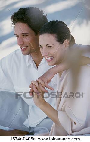 Young couple sitting together smiling View Large Photo Image Stock Image - Young couple sitting together smiling. Fotosearch