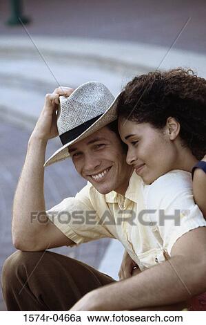 Stock Image - Young couple sitting together smiling. Fotosearch