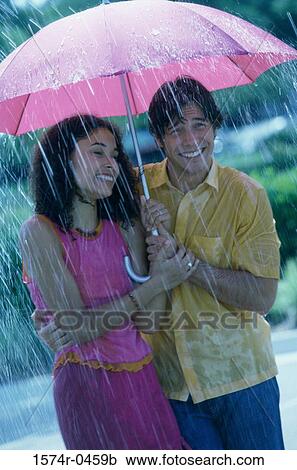 Young couple standing outdoors with an umbrella View Large Photo Image Stock Image - Young couple standing outdoors with an umbrella. Fotosearch