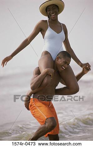 Young man carrying a young woman on his shoulders at the beach View Large Photo Image Stock Image - Young man carrying a young woman on his shoulders at the beach. Fotosearch