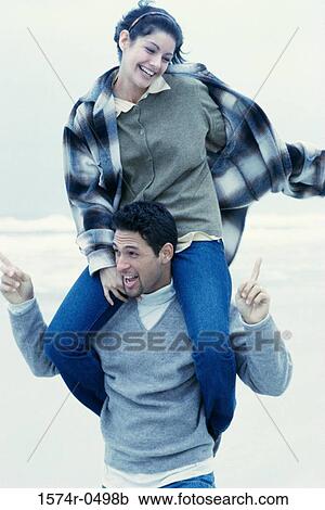 Stock Image - Young man carrying a young woman on his shoulders. Fotosearch