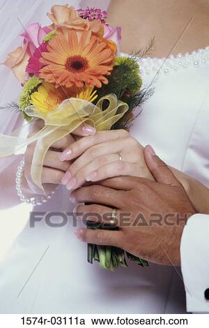 Bride and groom holding a bouquet of flowers together View Large Photo Image Stock Image - Bride and groom holding a bouquet of flowers together. Fotosearch