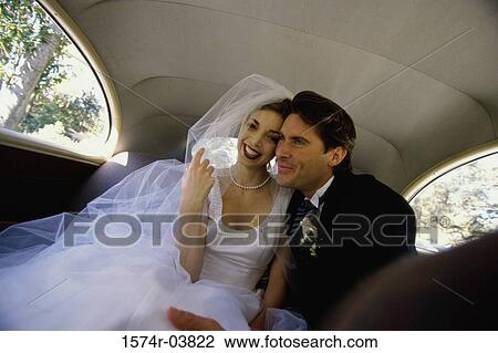 Stock Image - Bride and groom sitting in a car. Fotosearch