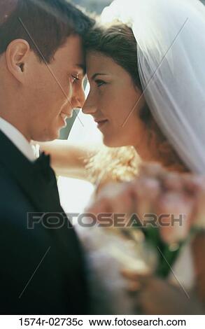 Stock Image - Close-up of a newlywed couple embracing each other. Fotosearch