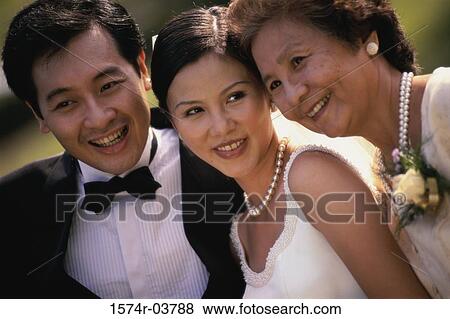 Stock Photo - Close-up of a newlywed couple smiling with a mature woman. Fotosearch