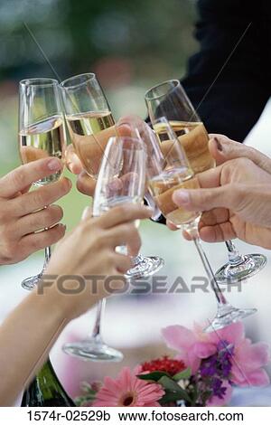 Stock Image - Close-up of peoples hands toasting with glasses of champagne. Fotosearch
