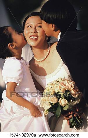 Stock Image - Flower girl and ring bearer kissing a bride. Fotosearch