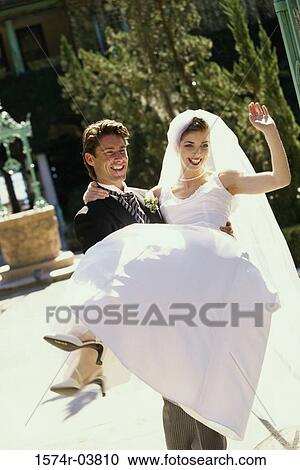 Stock Image - Groom lifting his bride. Fotosearch